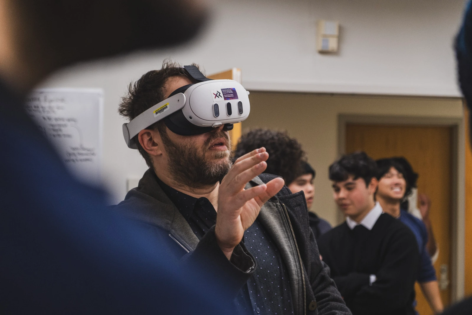 A visitor trying a Quest headset while students watch in the lab.
