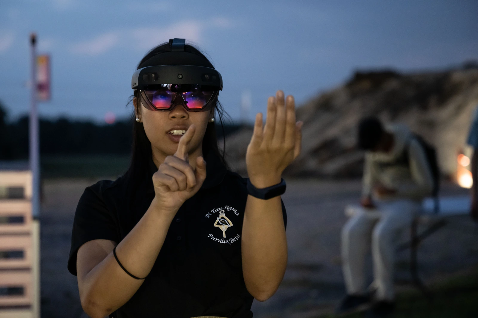 A person exploring a HoloLens outdoors, with both hands raised.